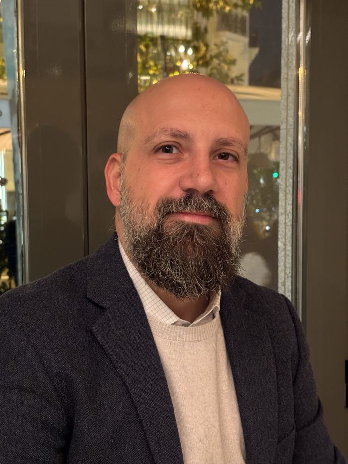 Portrait of Sergio smiling, in a navy blazer